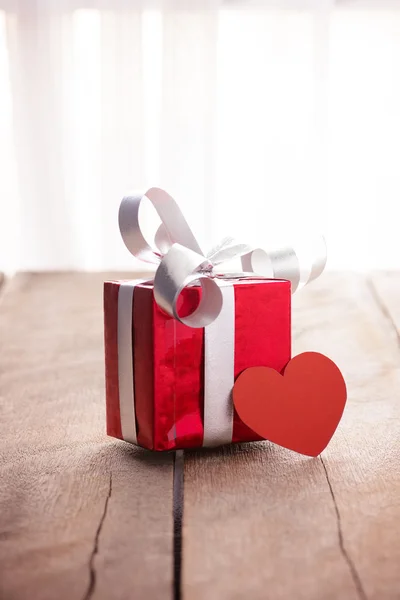 Red gift box and heart on white wooden table — Stock Photo, Image