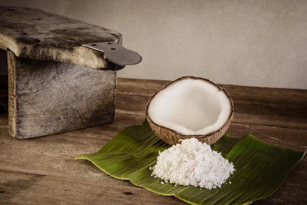 coconuts and coconut flakes on banana leaf and coconut grater