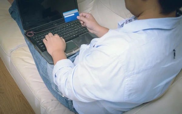 Close up de homem com computador portátil e cartão de crédito em casa — Fotografia de Stock