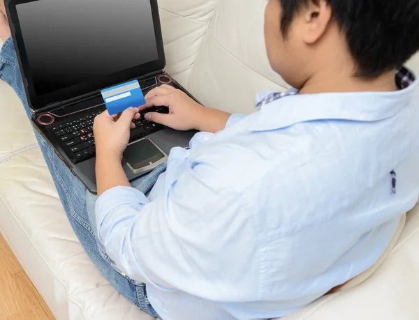 Primer plano del hombre con ordenador portátil y tarjeta de crédito en casa —  Fotos de Stock