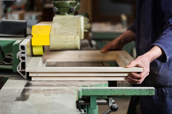 Carpenter's hands cutting wooden window frame