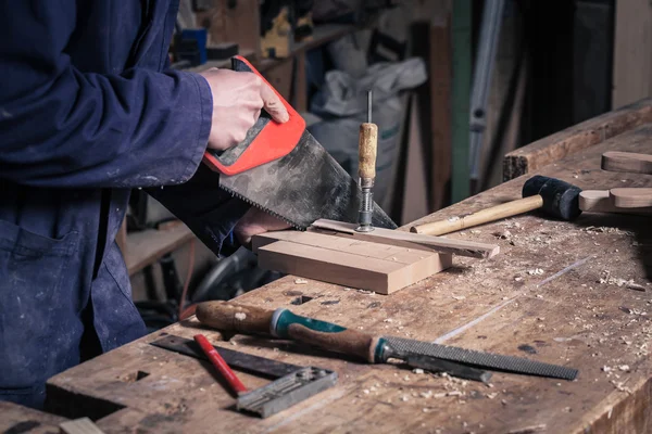 Carpintero aserrando un trozo de madera con una sierra manual —  Fotos de Stock