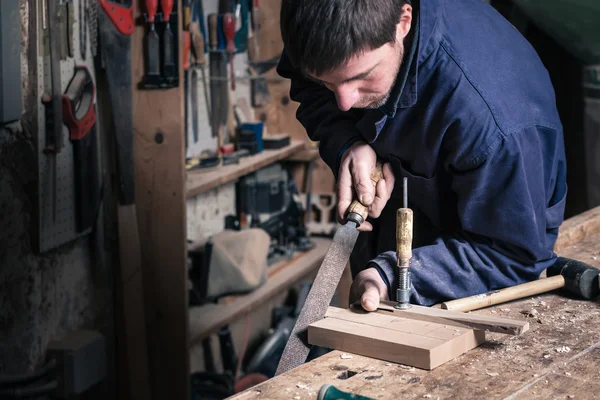 Carpintero trabajando en un tablero de corte de madera con un archivo — Foto de Stock
