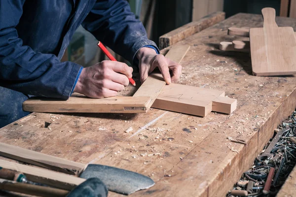 Carpintero trabajando en una tabla de cortar de madera con lápiz y regla —  Fotos de Stock