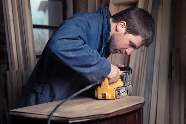 Carpintero restaurando muebles con lijadora de cinturón — Foto de Stock