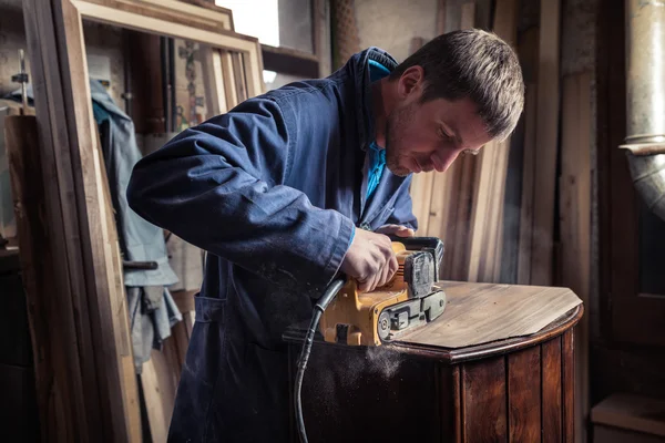 Carpintero restaurando muebles con lijadora de cinturón — Foto de Stock