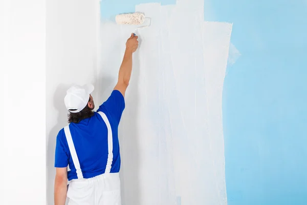 Pintor pintando una pared con rodillo de pintura — Foto de Stock