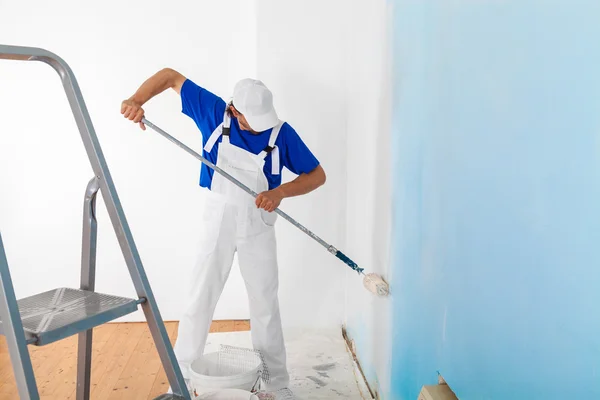 Pintor pintando uma parede com rolo de pintura — Fotografia de Stock