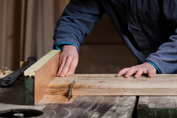 Carpenter je ruce dřevěné prkénko s pilu — Stock fotografie