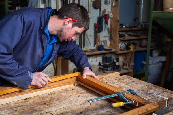 Carpintero trabajando en un marco de ventana de madera en su taller — Foto de Stock