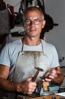 Çekiç ve ince gümüş parçaları tutan Goldsmith