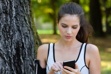 Genç kadın atlet akıllı telefonunu kullanarak