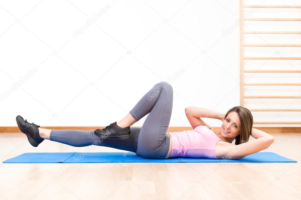 Young healthy woman in abs exercises