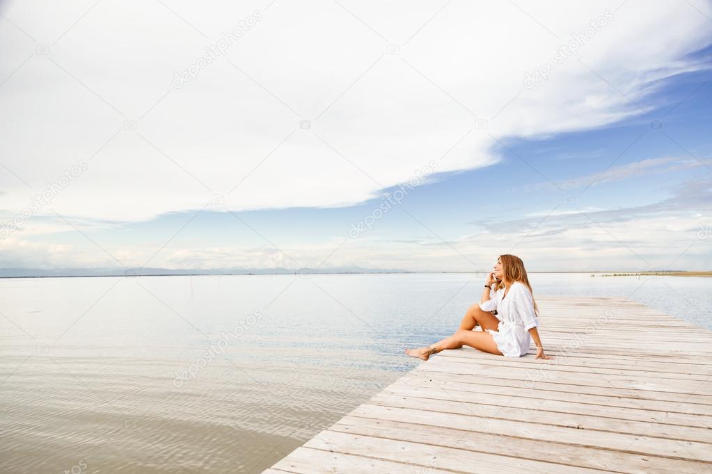 smiling Young woman talking on the phone on a pier