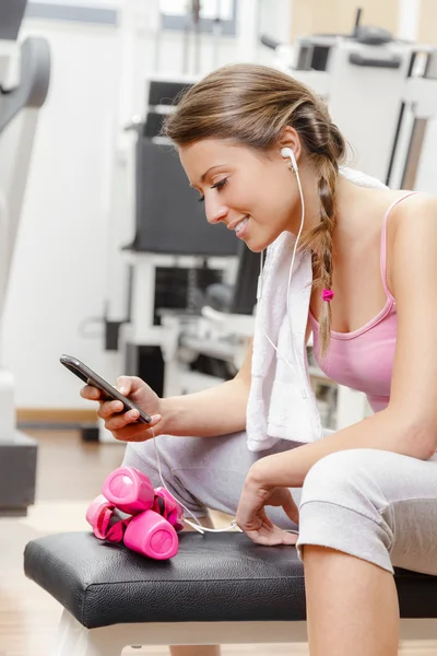 Leende kvinna med smartphone på gymmet — Stockfoto