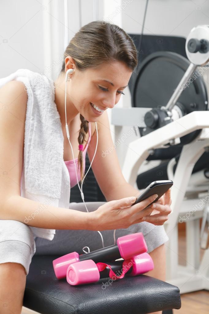 Smiling woman using smart phone at the gym