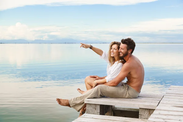 Lächelndes Paar sitzt und zeigt auf den Horizont — Stockfoto