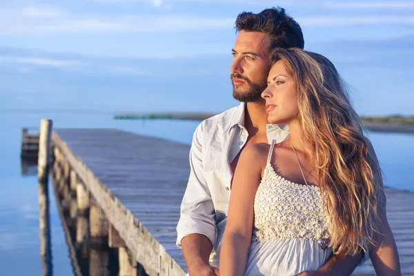 Man omfamnar sin kvinna bakifrån på seaside bakgrund under — Stockfoto