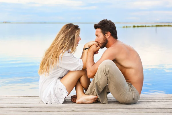 Couple sitting on a jetty under a blue sky at a sunset Stock Image