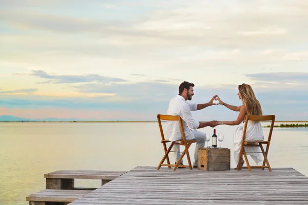 Coppia di cuore plasmando con le mani al mare — Foto Stock