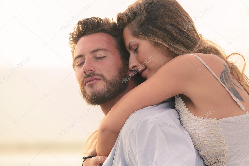 woman embracing her man from behind at sunset