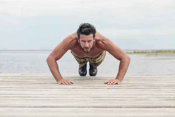 Athletic armén gör Push motion på stranden — Stockfoto