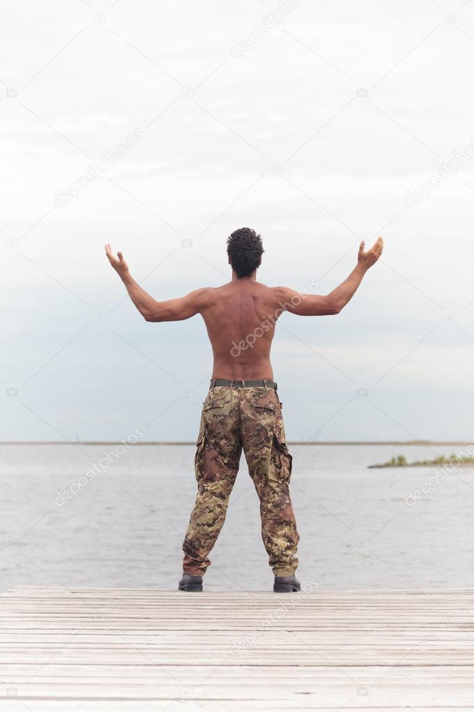 Rear View of Athletic Topless Soldier at the Beach