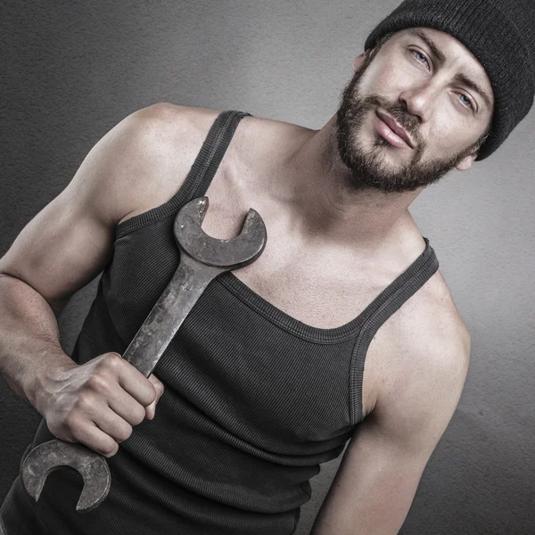 Hombre guapo de pie y sosteniendo una llave inglesa —  Fotos de Stock