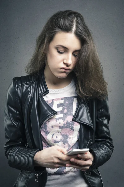 Tired girl looking at phone with bored emotion on her face — Stock Photo, Image