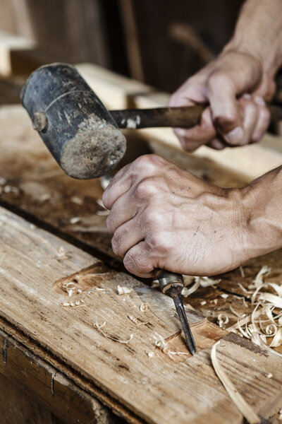 carpenter hands working with a chisel and hammer