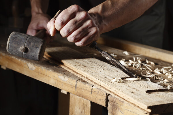 carpenter hands working with a chisel and hammer