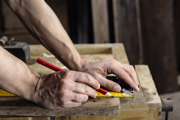 плотник измеряет деревянную доску
