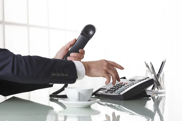 Businessman hands dialing out on a black deskphone — Stock Photo, Image