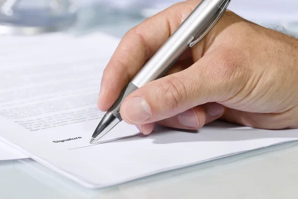 Close-up shot of hand signing a document Stock Picture