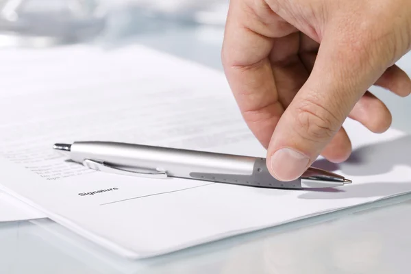Close-up of a hand taking a pen to fill and sign documents. Stock Picture