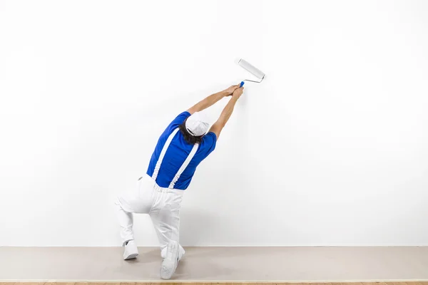 白い壁に paintroller としゃがむの画家 — ストック写真