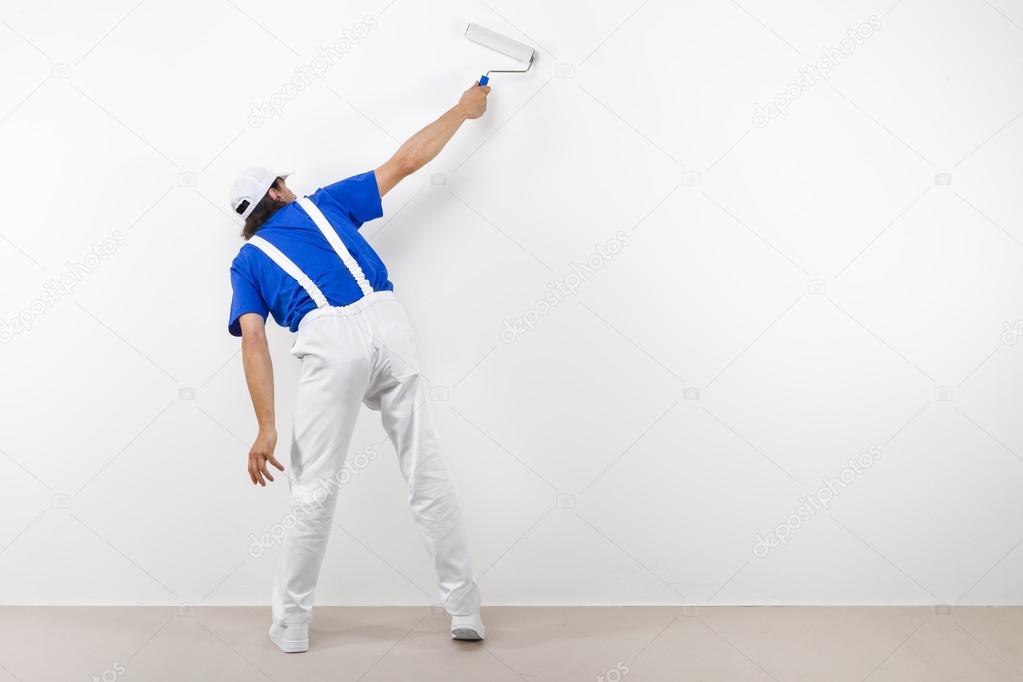 Painter with paintroller on white wall