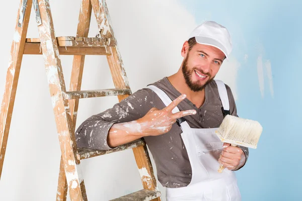 Painter in white dungarees with victory gesture — Stock Photo, Image