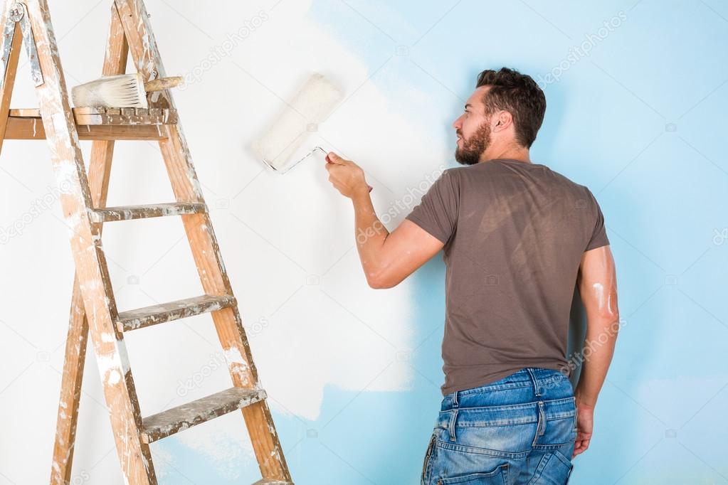 painter in paint splattered shirt painting a wall
