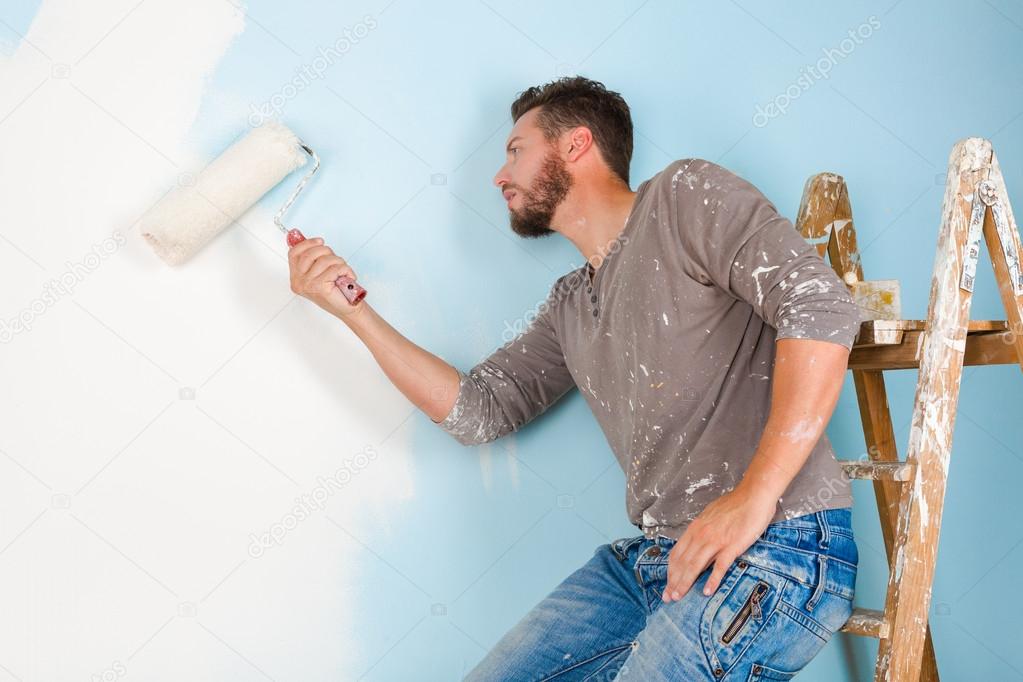 painter in paint splattered shirt painting a wall
