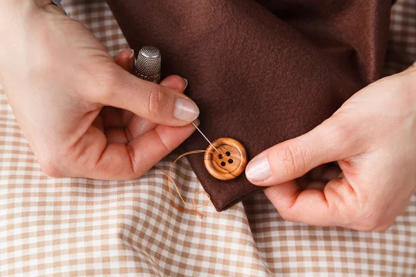 Mulher Mãos botão de costura no tecido — Fotografia de Stock