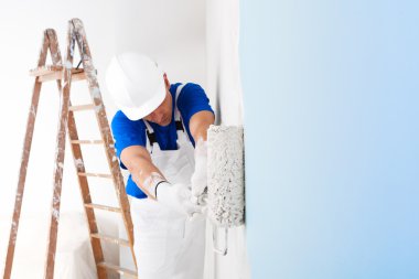 ressam bir duvar boya silindiri ile boyama