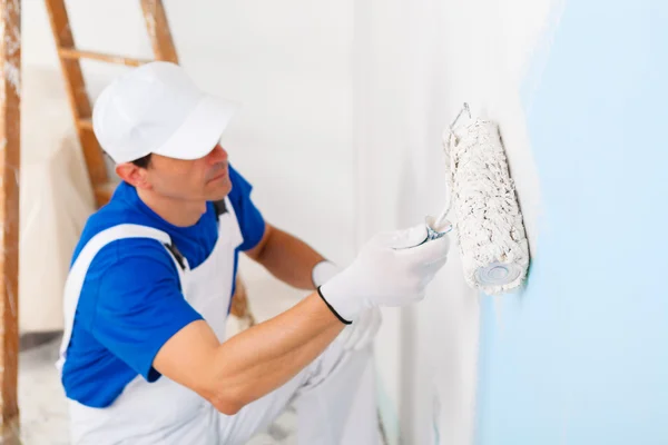 Pintor pintando uma parede com rolo de pintura — Fotografia de Stock