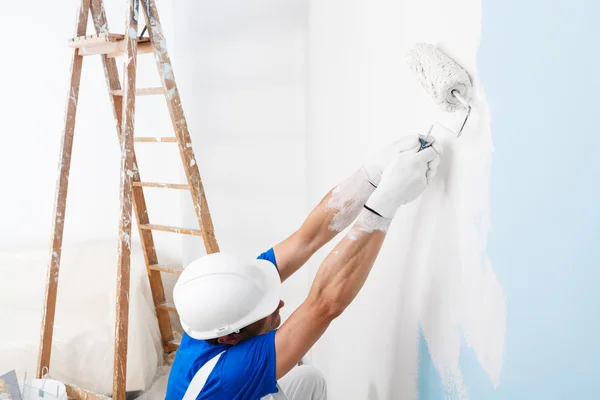 Pintor pintando una pared con rodillo de pintura — Foto de Stock