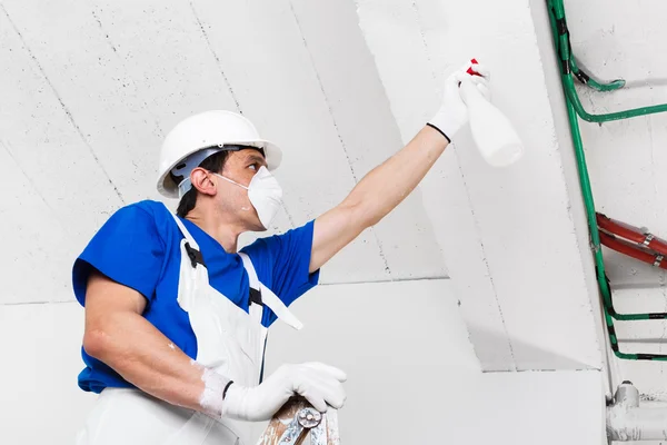 Werknemer spuiten plafond met sproeiflacon — Stockfoto