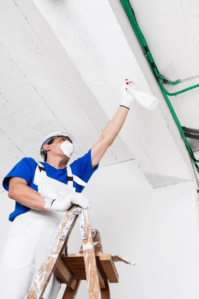 Trabalhador tecto pulverização com frasco de spray — Fotografia de Stock