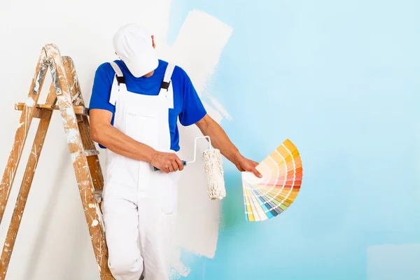 Pintor com paintroller mostrando uma paleta de cores — Fotografia de Stock