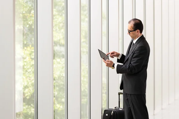 Hombre de negocios utilizando la tableta cerca de grandes ventanas — Foto de Stock