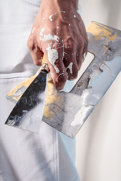 Workman Hand holding Putty Knife with Plaster