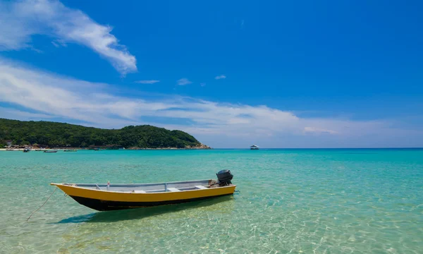 Barco junto a la playa con agua clara y cielos azules —  Fotos de Stock